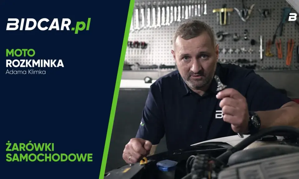 Mężczyzna trzymający żarówkę samochodową w warsztacie.