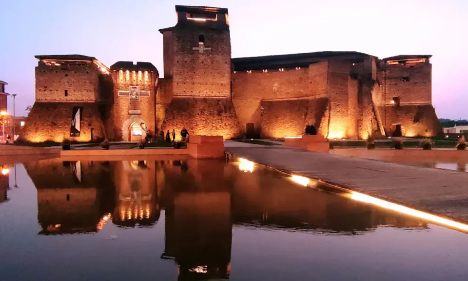 Castello Sismondo illuminato di sera, con riflessi sull'acqua. Un luogo che evoca la magia del cinema, come un museo felliniano a Rimini.