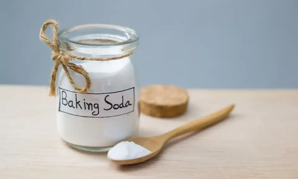 Słoik z napisem "Baking Soda" i drewniana łyżka z proszkiem. To naturalny sposób na usuwanie plam.