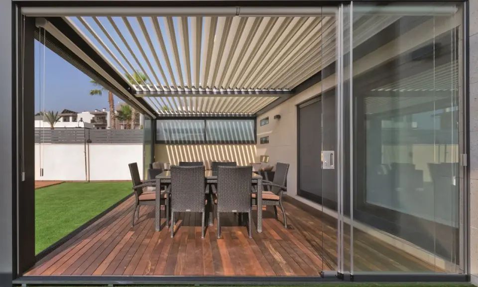 Porches cerrados con encanto, con mesa y sillas de mimbre sobre tarima de madera y césped artificial.