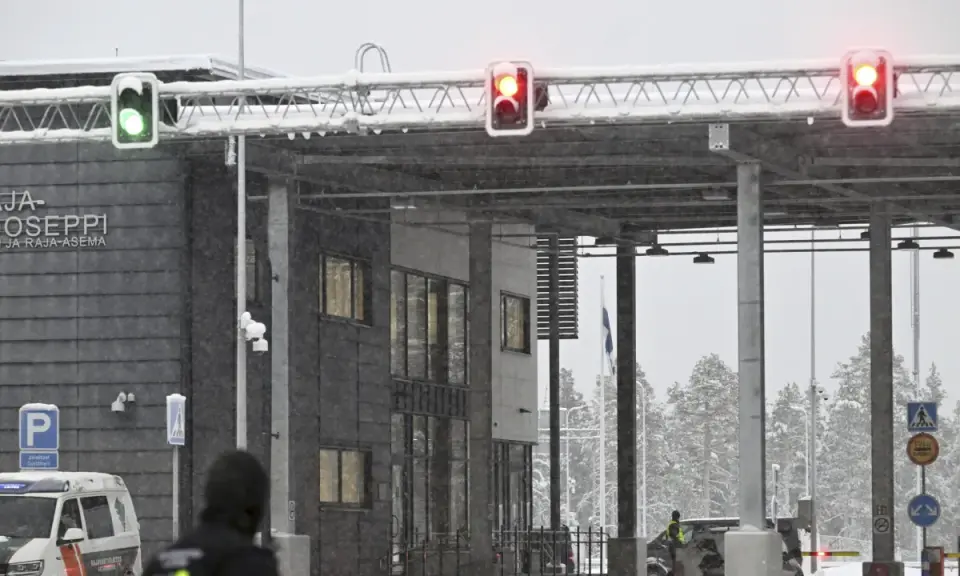 Grön trafiksignal vid gränsövergången Joensuu, Finland. Snö faller över byggnaden och träden. En polisbil syns. Gränsen mellan Ryssland och Finland är stängd.