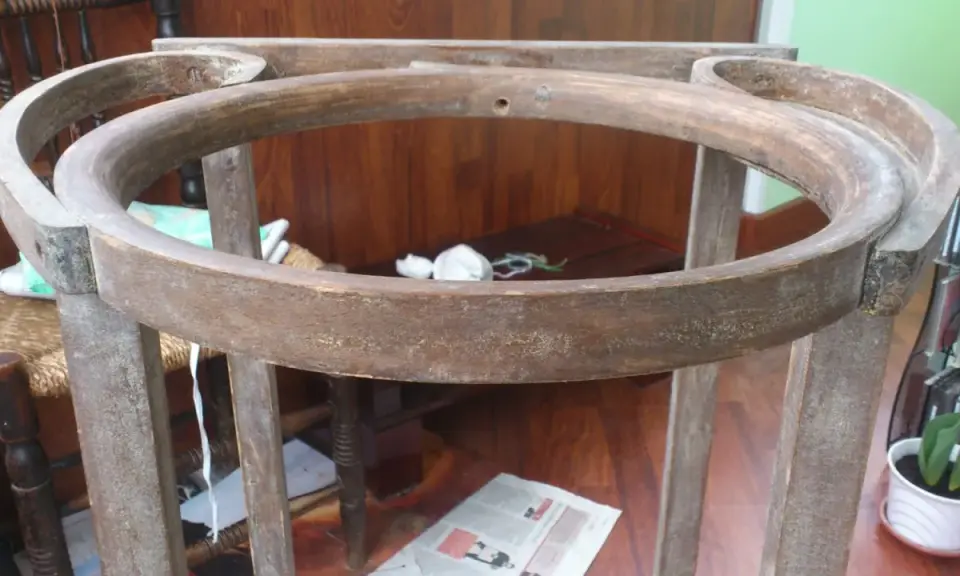 Estructura de madera de un palanganero antiguo, lista para restaurar. Se aprecian sus patas y el aro superior curvo.