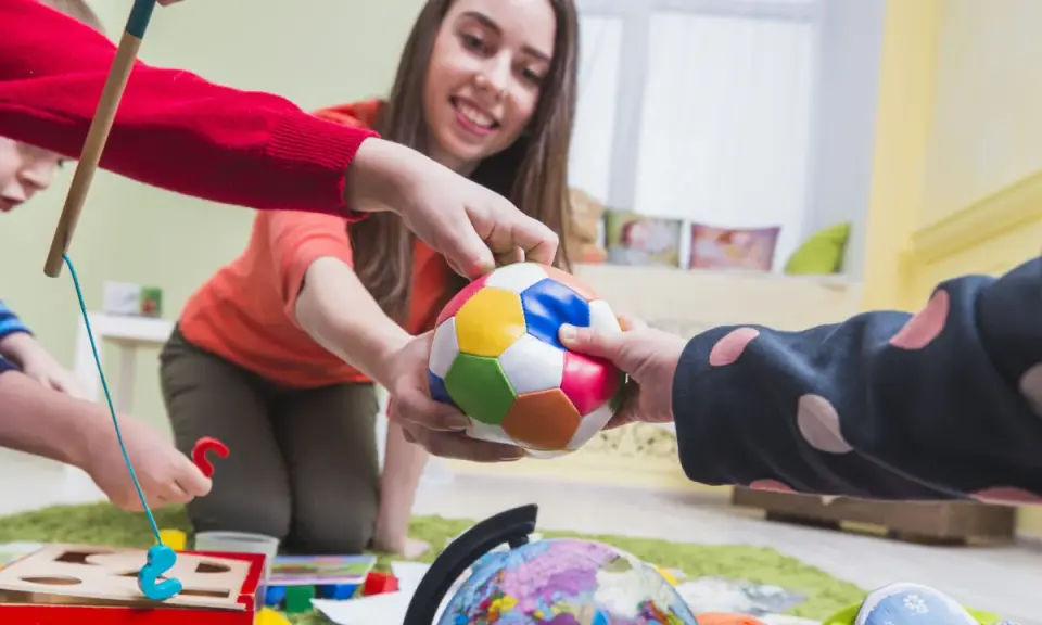 Bambini e terapista giocano con una palla colorata, un globo e un gioco di incastri. La terapia occupazionale cos'è? È questo: gioco e apprendimento.