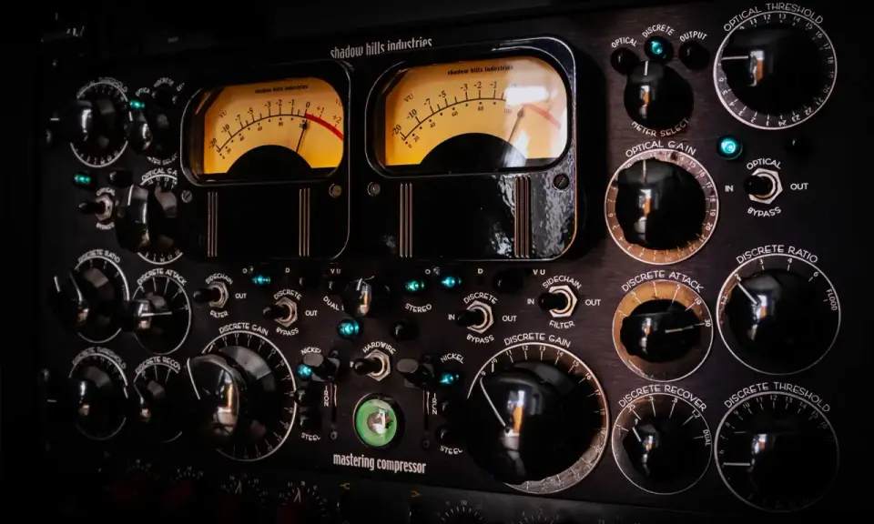 Panneau de compresseur mastering avec deux VU-mètres lumineux. Apprenez comment utiliser un compresseur en ajustant les nombreux boutons et sélecteurs.