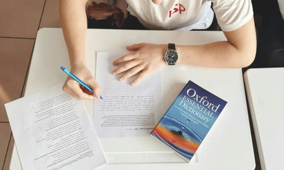 Uczeń pisze wypracowanie, a obok leży słownik "Oxford Essential Dictionary". Zastanawia się, co to jest "suffix" i jak go użyć.