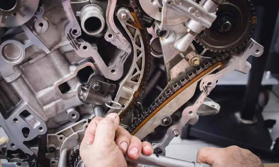 Mechanik naprawia rozrząd silnika. Luźny łańcuch może być jednym z objawów zużytej poduszki silnika.