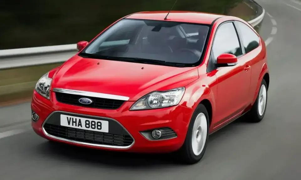 Czerwony Ford Focus MK2 1.6 benzyna w wersji 3-drzwiowej, jadący po zakręcie drogi.