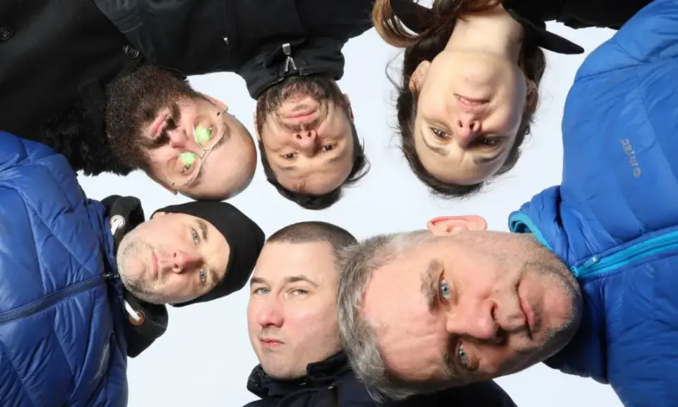 Grupa ludzi, w tym jeden z okularami, tworzy afro kolektyw. Wszyscy patrzą w obiektyw, tworząc ciekawe ujęcie.