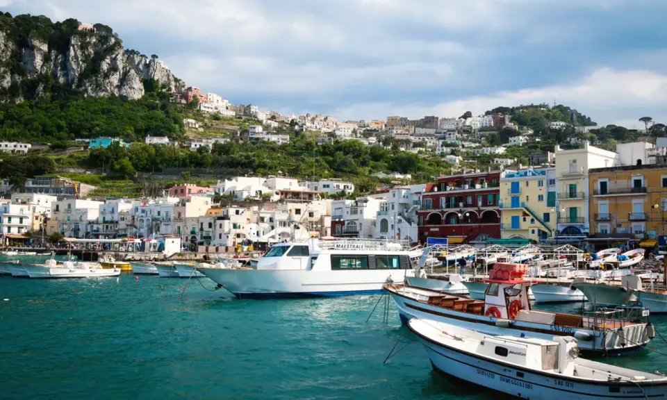 Barche nel porto di Capri, con la città arroccata sulla collina. Un ottimo punto di partenza per capire come raggiungere Capri da Napoli.
