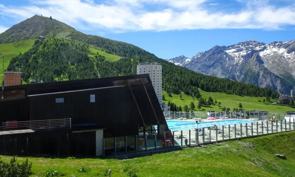 Una splendida piscina in montagna in Piemonte, con vista su verdi colline e cime innevate.