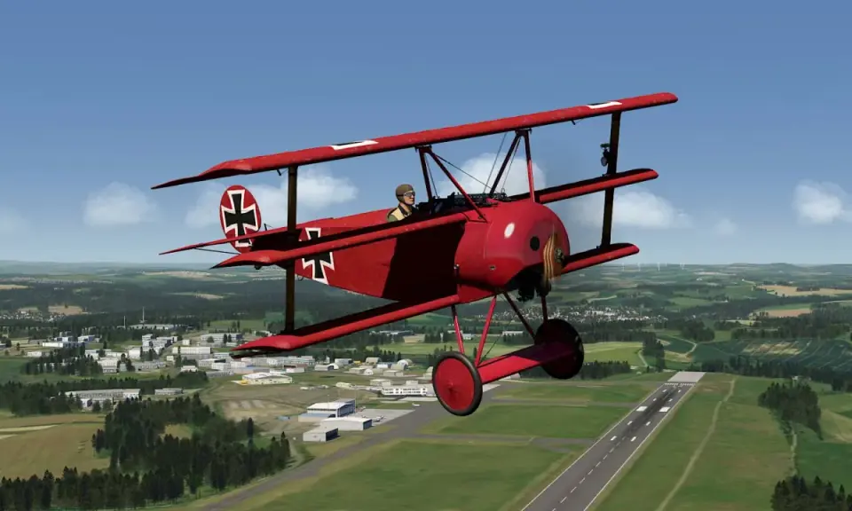Ein rotes Fokker-Flugzeug mit Eisernem Kreuz fliegt über eine grüne Landschaft mit einer Stadt und einem Flugfeld.