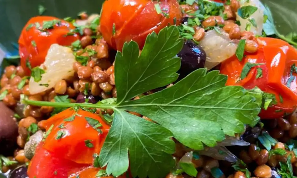 Ensalada de lentejas con tomates cherry, aceitunas negras y perejil fresco. Un plato saludable y lleno de sabor.