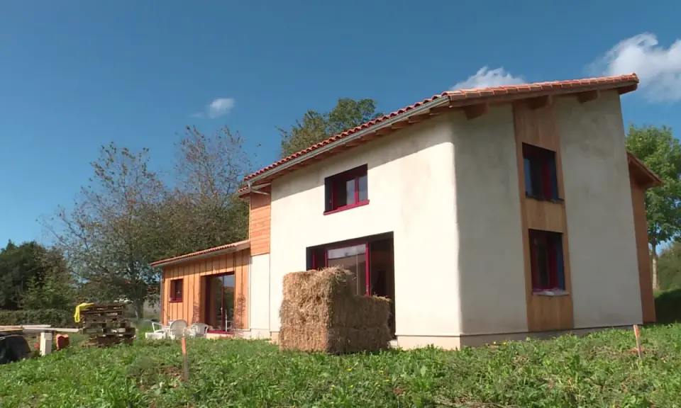 Maison écologique en paille, un projet de prix maison en paille clé en main. Le bâtiment est en cours de finition, avec des murs enduits et des accents de bois.