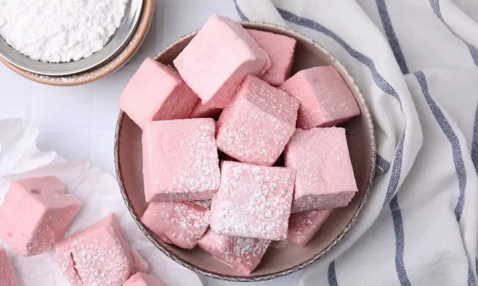 Dulces cubos rosados, como se hacen las nubes de azúcar, espolvoreados con azúcar glas.