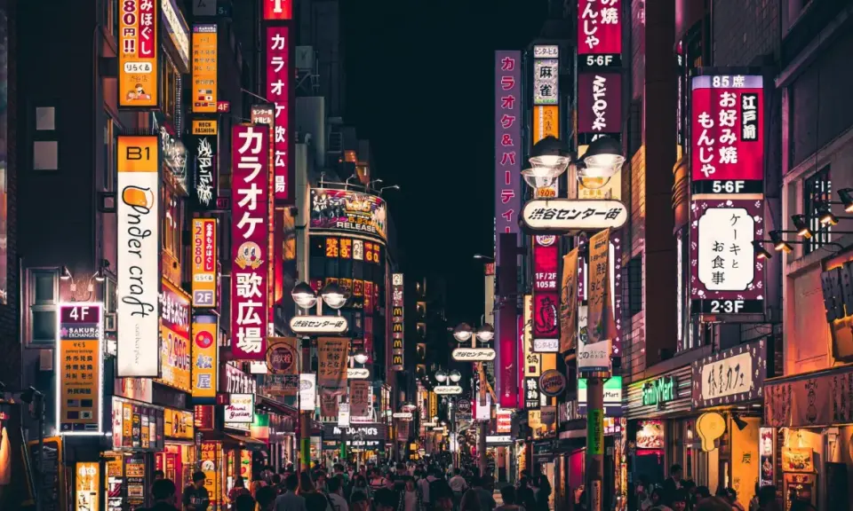 Nocne życie Tokio, neonowe szyldy zapraszają, kiedy do Japonii. Tłumy ludzi spacerują ulicami pełnymi barów i sklepów.