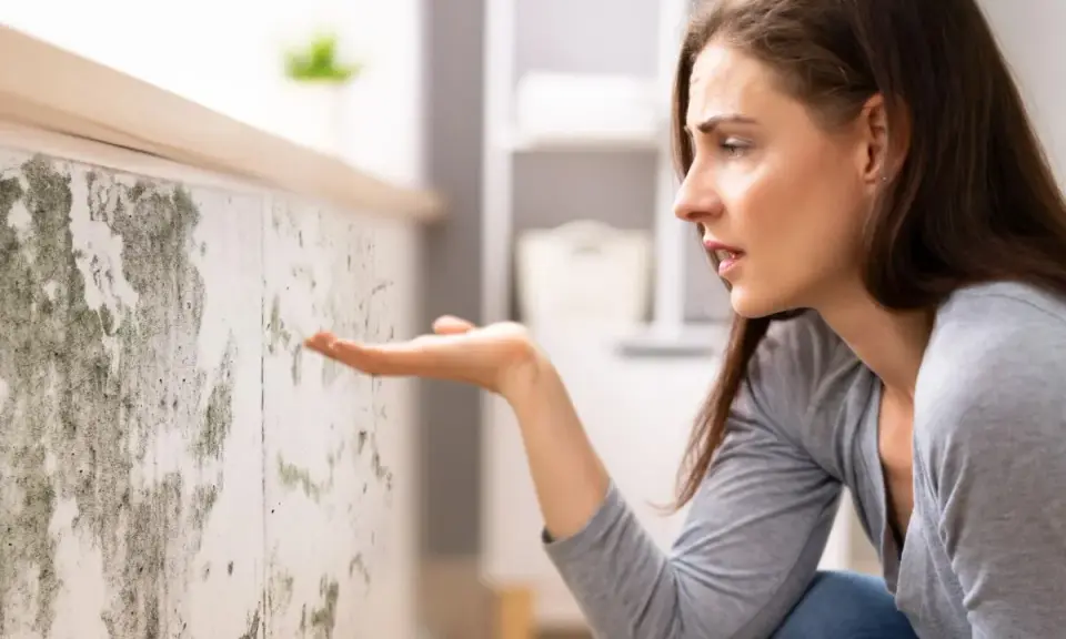 Donna preoccupata osserva muffa su muro, cercando soluzioni su come eliminare umidità in casa.