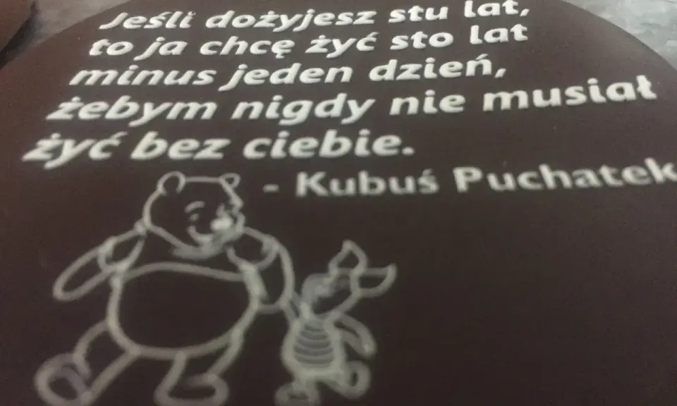 Czekoladowy medalion z cytatem Kubusia Puchatka i rysunkiem Kubusia i Prosiaczka.