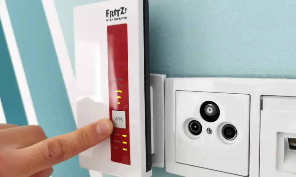 Fritz! WLAN Repeater verbessert das Signal, um **WLAN durch Betondecke** zu leiten. Ein Finger drückt auf die WPS-Taste.