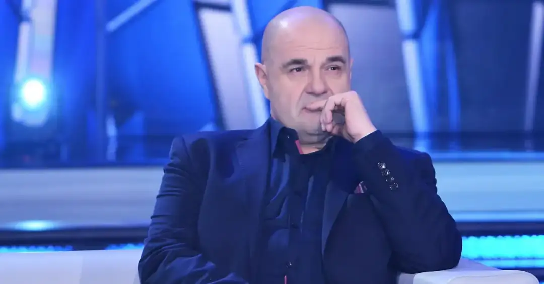 Cezary Żak w eleganckim garniturze, zamyślony, jakby przygotowywał się do roli w teatrze.