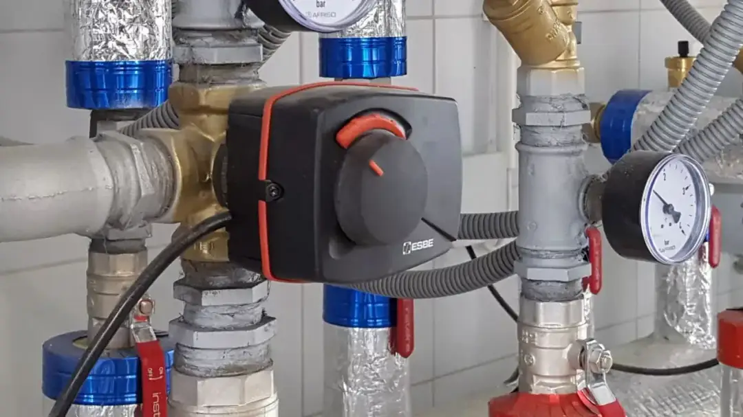 Montaż zaworów wody z termostatycznym regulatorem ESBE. Widoczne manometry i izolowane rury.