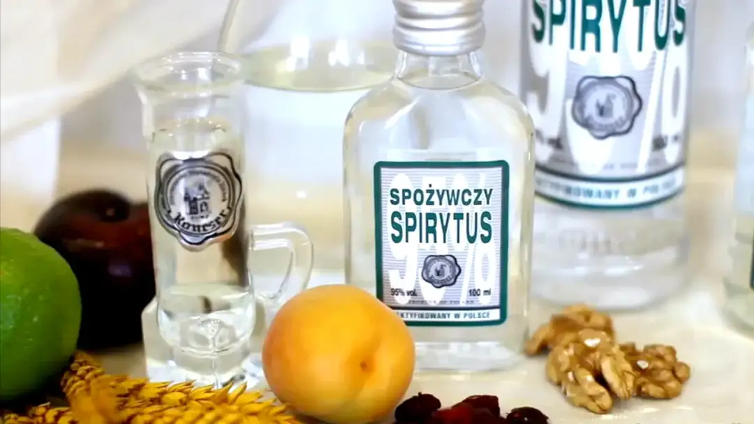 Butelki spirytusu, kieliszek, owoce i orzechy. Pokazuje, jak się robi spirytus.