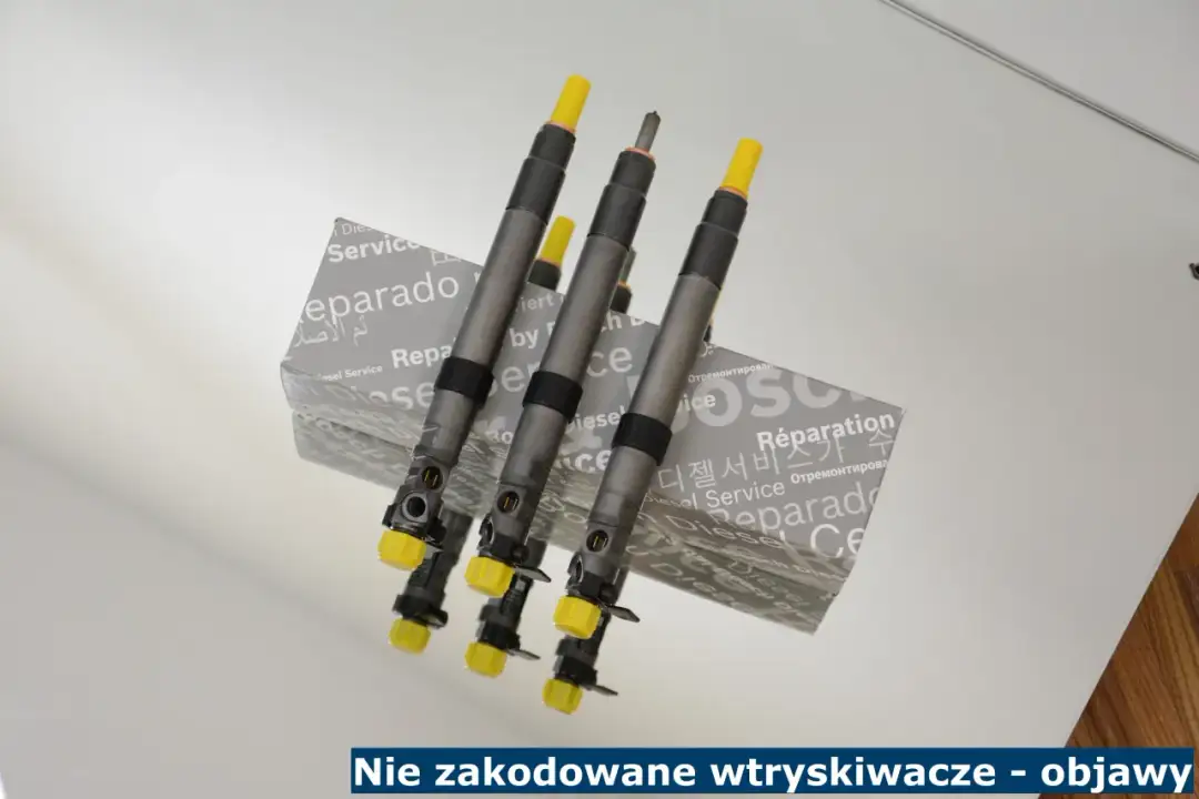 Trzy wtryskiwacze diesla z żółtymi osłonkami, leżące na pudełku z napisem "Diesel Service". Objawy nie zakodowane wtryskiwacze.
