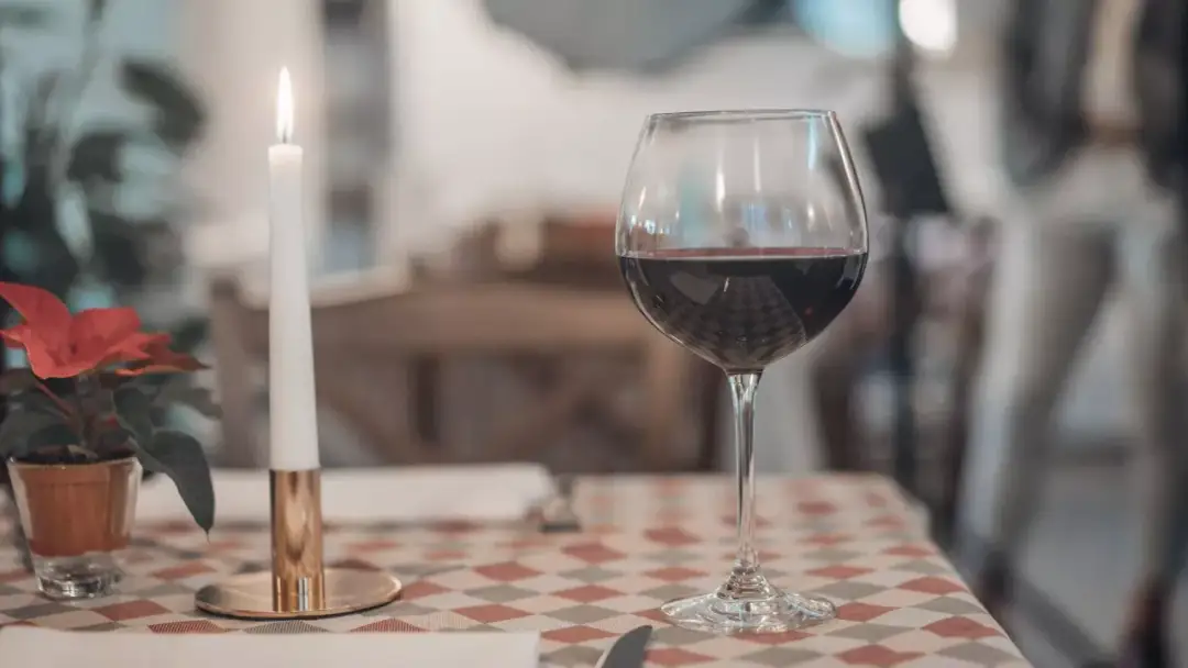 Romantyczny wieczór przy świecy i kieliszku czerwonego wina. Czy można pić wino po terminie przydatności na etykiecie? To pytanie pozostaje otwarte.