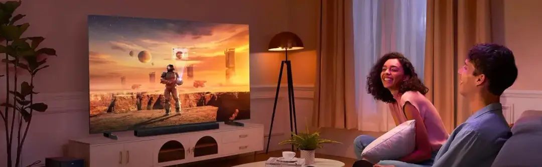 Para młodych ludzi śmieje się, oglądając film na dużym ekranie. Czy na monitorze można oglądać telewizję? Tak, ten ekran oferuje wrażenia jak z kina!