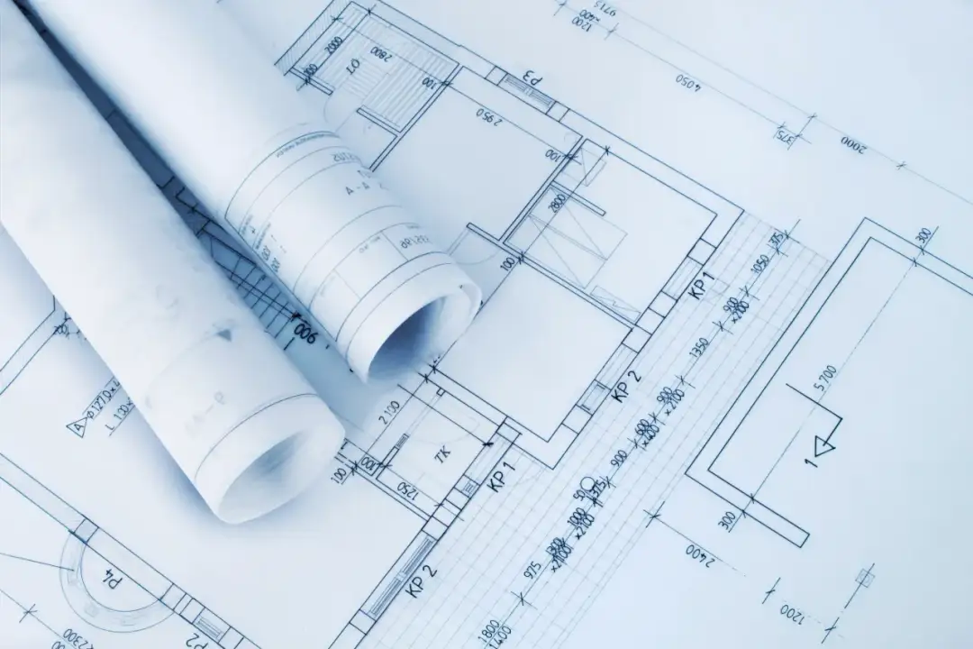 Zrolowane dokumenty z projektem architektoniczno budowlanym, ukazujące plany pomieszczeń i wymiary.