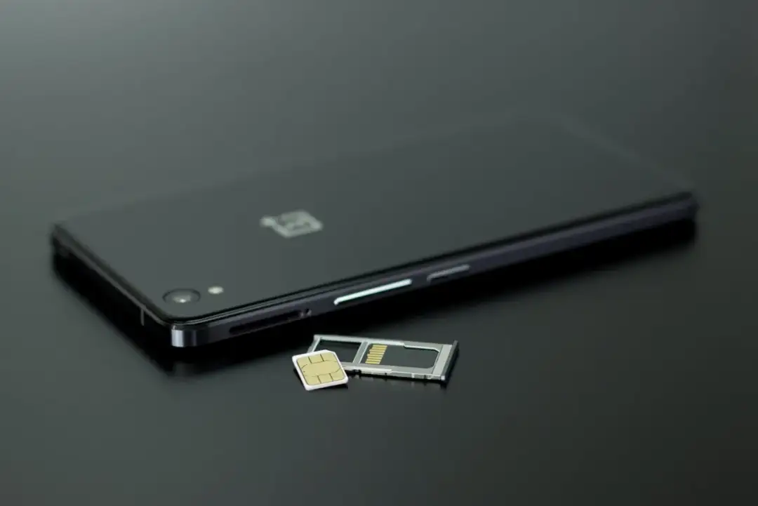 Czarny smartfon z tacką na kartę SIM i kartą pamięci obok. Dowiedz się, jak przenieść zdjęcia z telefonu na kartę pamięci.