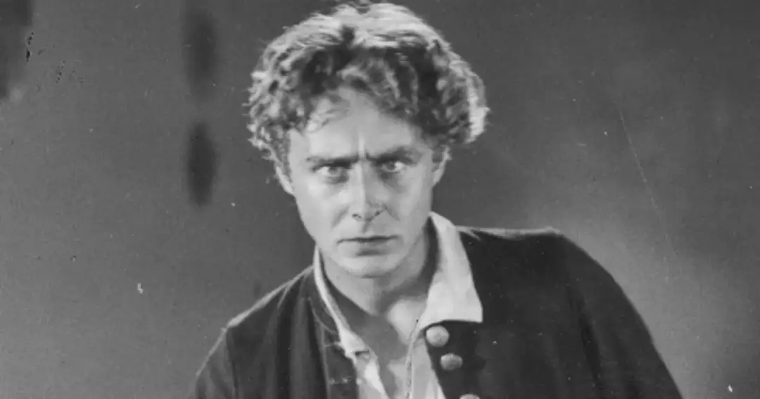 Portret mężczyzny z burzą loków, w stroju przypominającym historyczny. Czy to on, kto wynalazł kino?