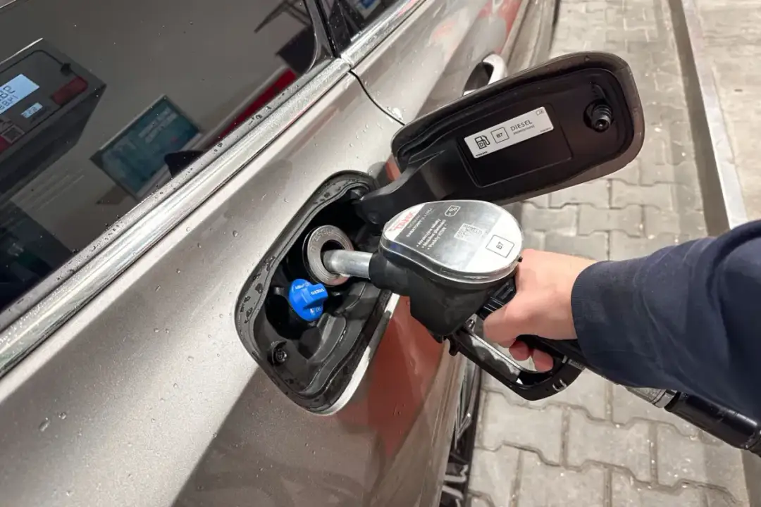 Tankowanie samochodu. Dłoń trzymająca pistolet z dystrybutora, wlewana jest do baku **olej napędowy**.