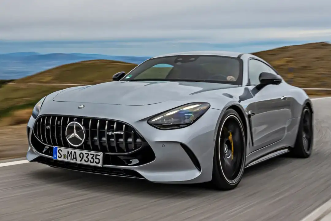 Srebrny Mercedes GT 63 AMG pędzi po krętej drodze, ukazując swoją sportową sylwetkę na tle górskiego krajobrazu.