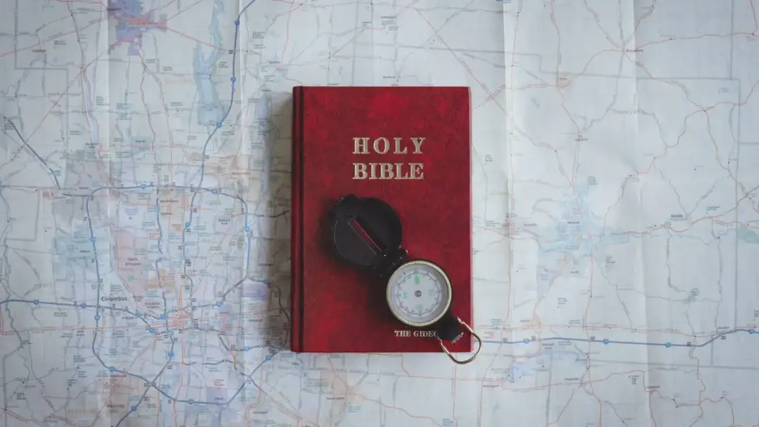Czerwona Biblia i kompas na mapie. Pismo Święte wskazuje drogę, jak nie cudzołożyć, co to znaczy żyć w zgodzie z Bogiem.