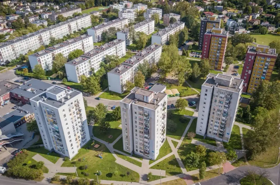 Widok z lotu ptaka na osiedle z blokami mieszkalnymi i drzewami.