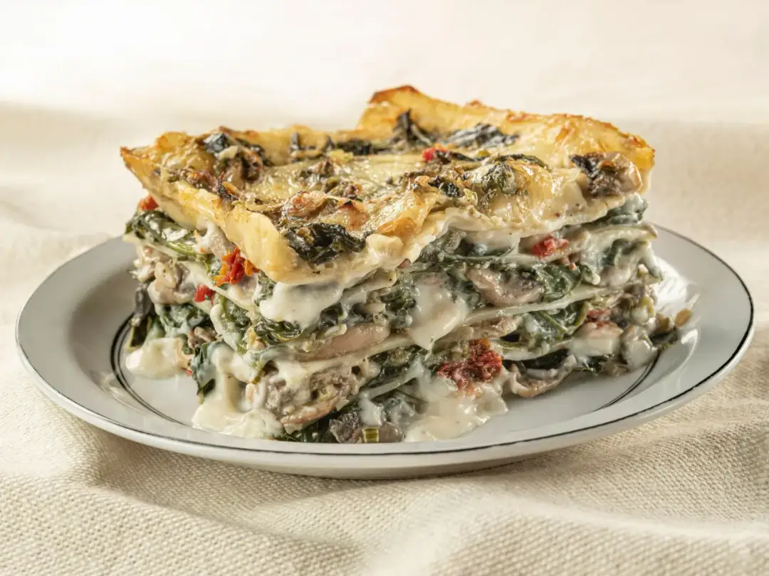 Pyszna lasagne ze szpinakiem i grzybami, podana na talerzu. Idealna propozycja, co zamiast wina do lasagne, gdy szukasz czegoś lekkiego.