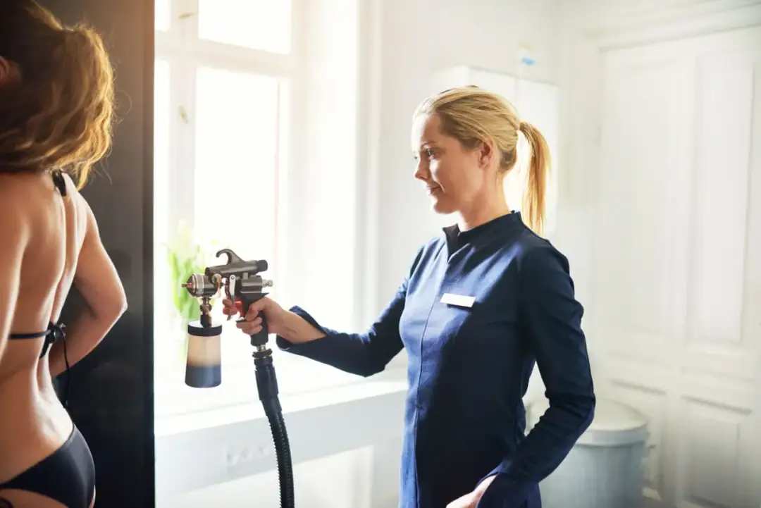 Profesjonalistka wykonuje opalanie natryskowe. Dowiedz się, ile kosztuje opalanie natryskowe i uzyskaj piękny, równomierny koloryt skóry.