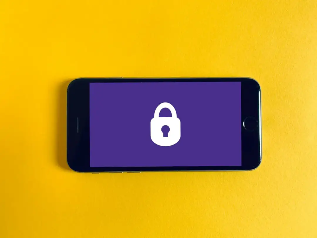Smartfon z ikoną kłódki na fioletowym tle, symbolizującą wzory blokady telefonu i bezpieczeństwo danych.