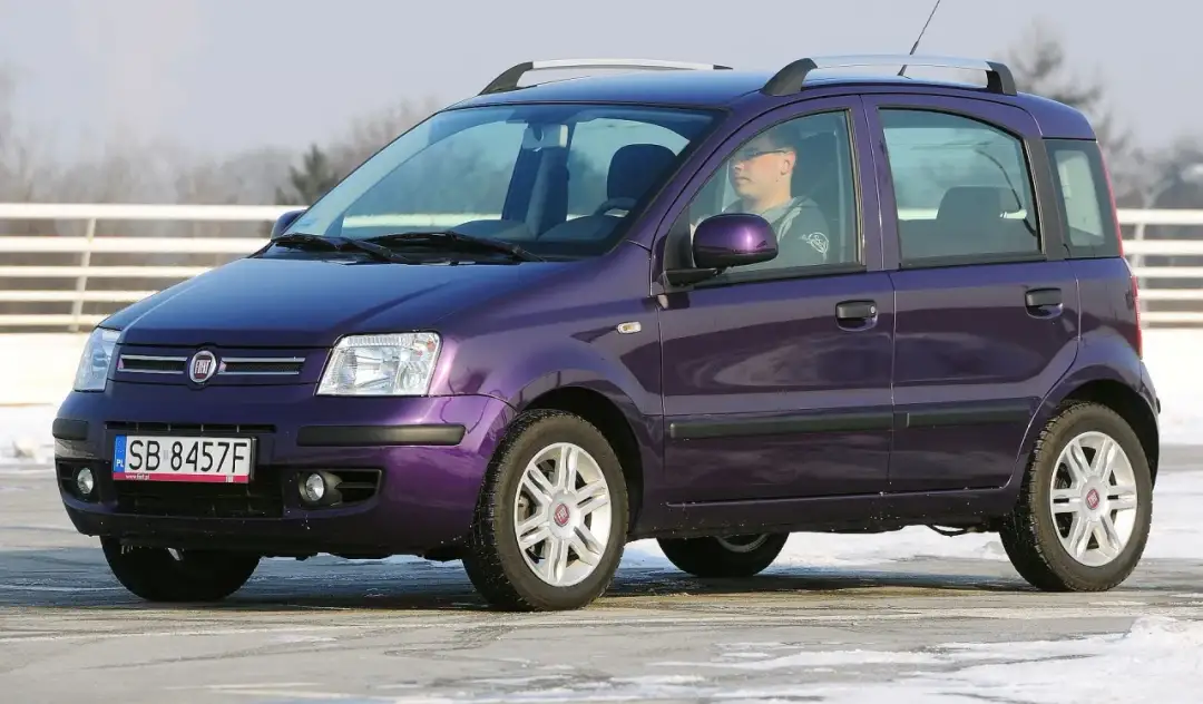 Fioletowy Fiat Panda, idealny jako jedno z aut do 15 tys. zł, z kierowcą za kierownicą.