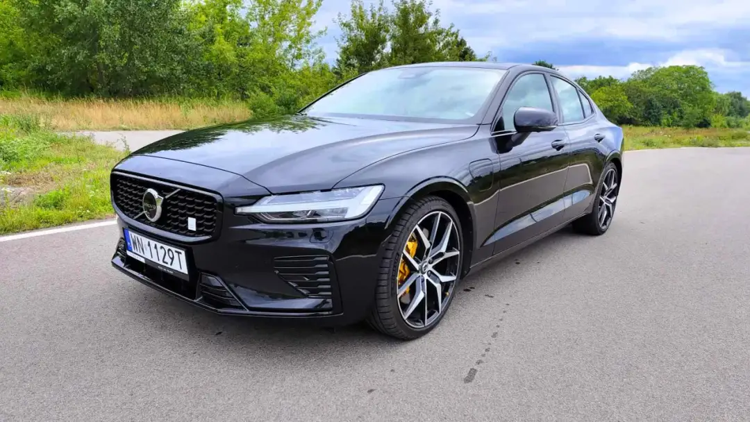 Czarny Volvo S60 V8 z żółtymi zaciskami hamulcowymi na tle zieleni.