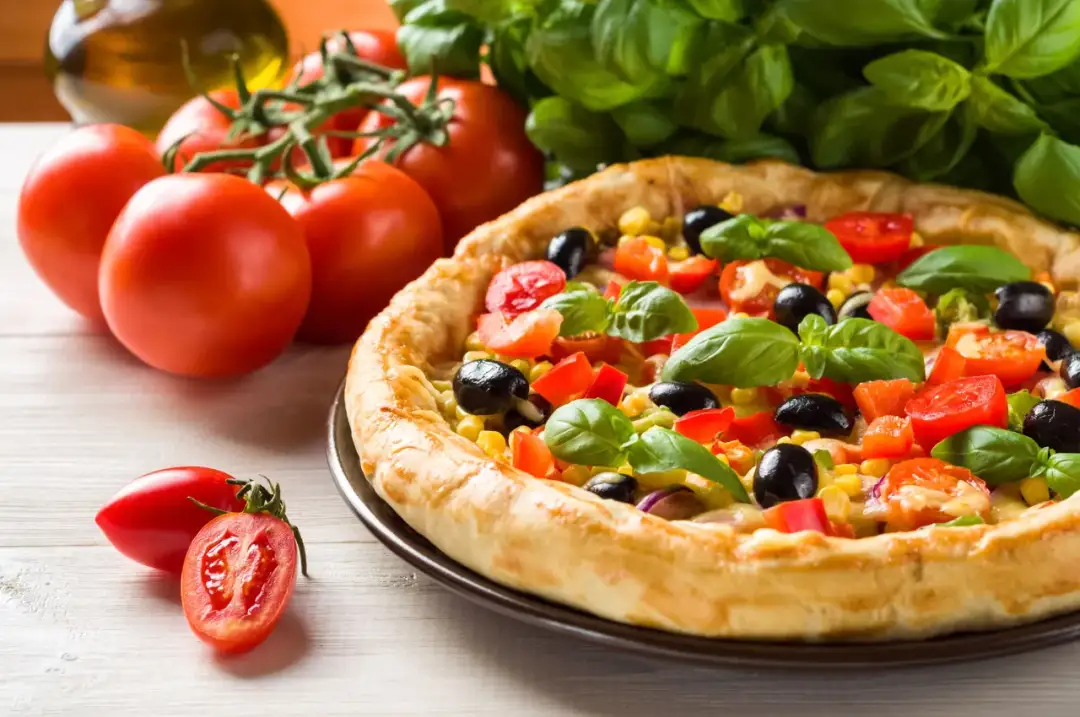 Gotowa pizza z pomidorami, oliwkami i kukurydzą, tuż przed podaniem. Idealny czas pieczenia pizzy!