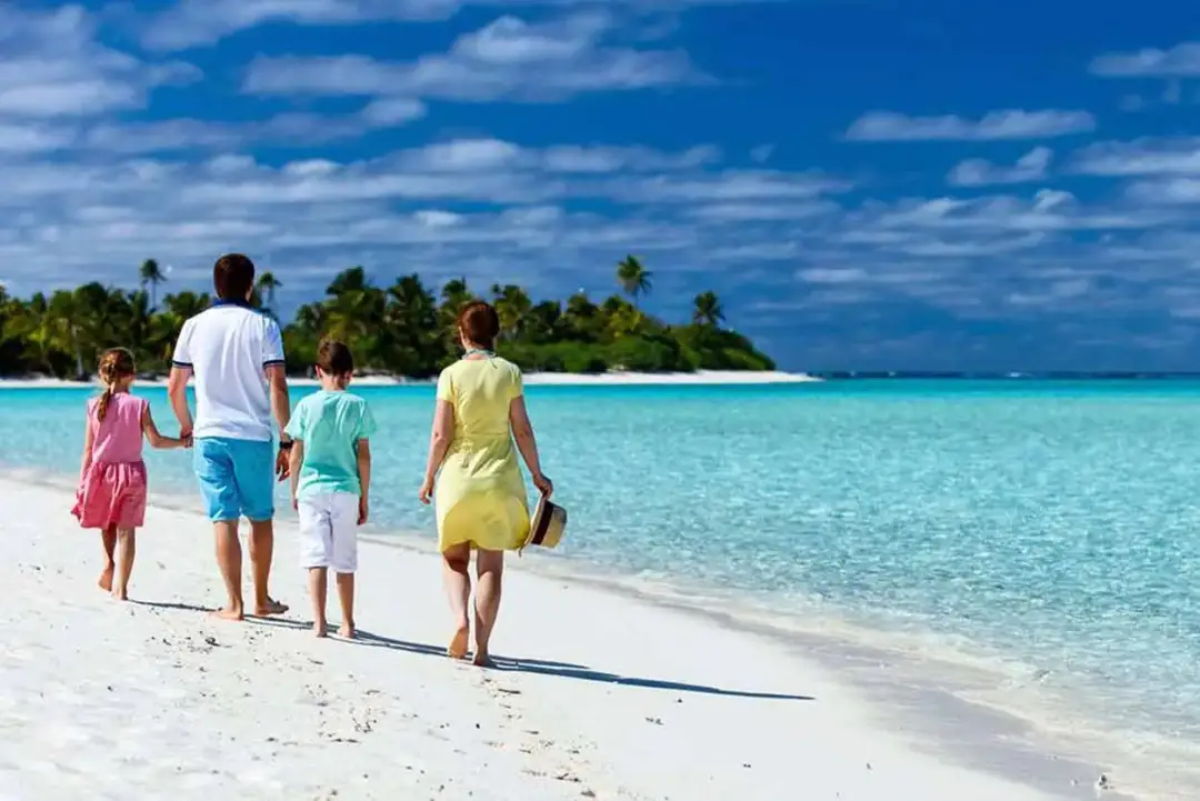 Rodzina spaceruje po rajskiej plaży. Idealne miejsce, gdzie jechać z rocznym dzieckiem na wakacje marzeń.