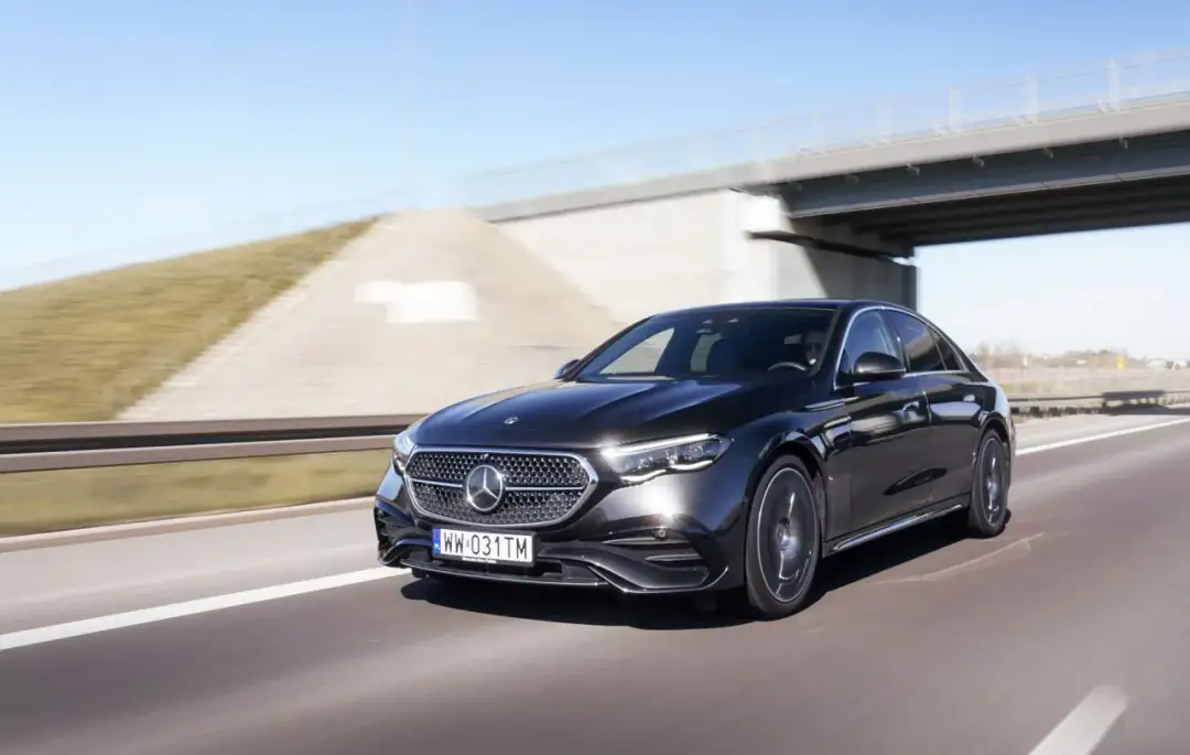 Elegancki, czarny Mercedes E220d mknie autostradą pod błękitnym niebem.