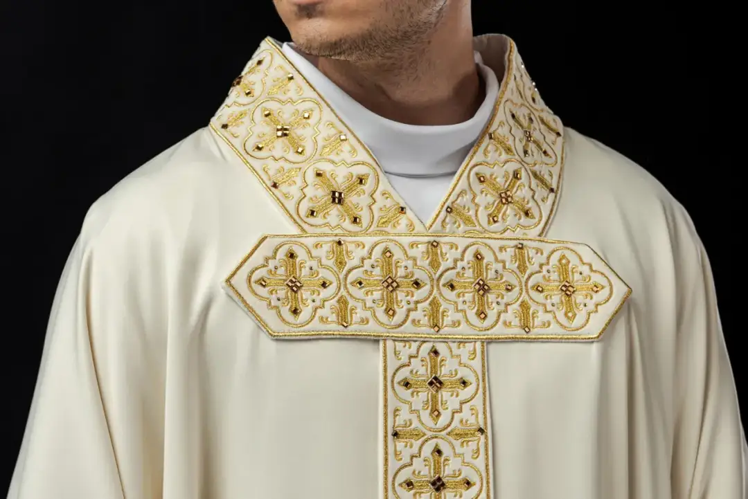 Biała szata liturgiczna z bogatymi złotymi haftami i krzyżami. Prośba o modlitwę w intencji kapłana.
