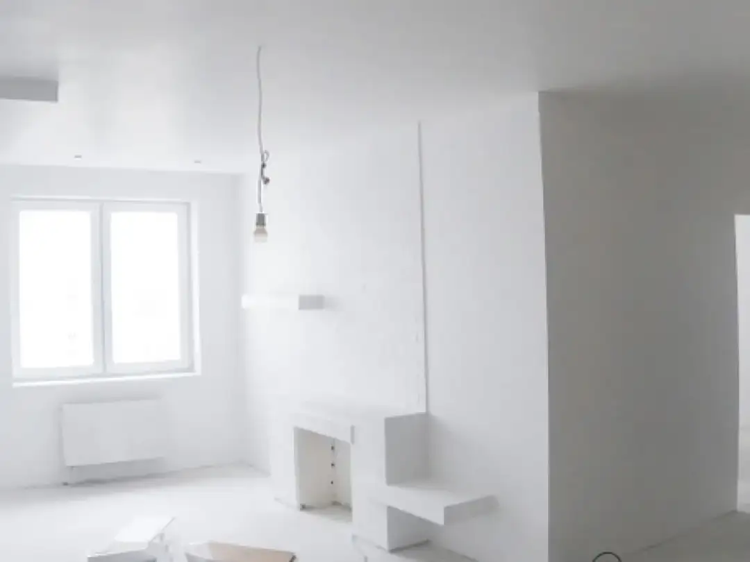 Nowe, ciekawe zabudowy z płyt gipsowych tworzą nowoczesny kominek i półki. Pokój w trakcie remontu.