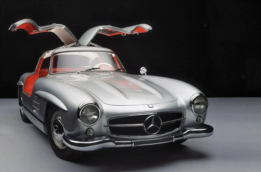 Srebrny Mercedes 300 z otwieranymi do góry drzwiami, prezentujący swoje kultowe skrzydła.