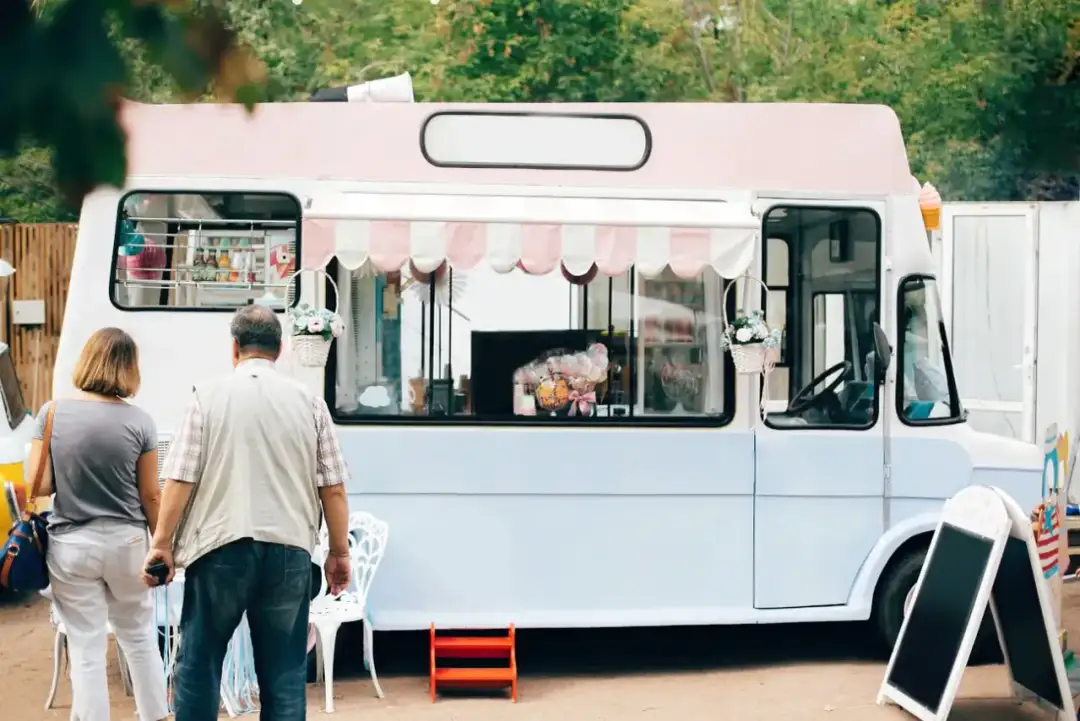 Para food trucków i handlu obwoźnego: jakie są wymogi sanepidu? Uroczy food truck z lodami, para klientów.