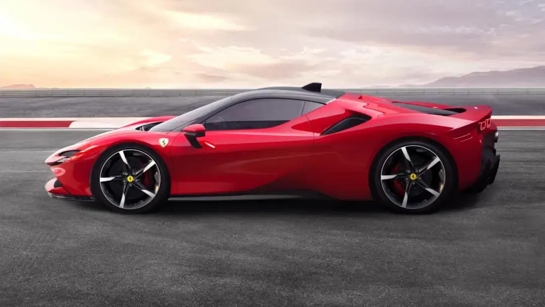 Czerwone Ferrari SF90 na torze wyścigowym, z zachodem słońca w tle.