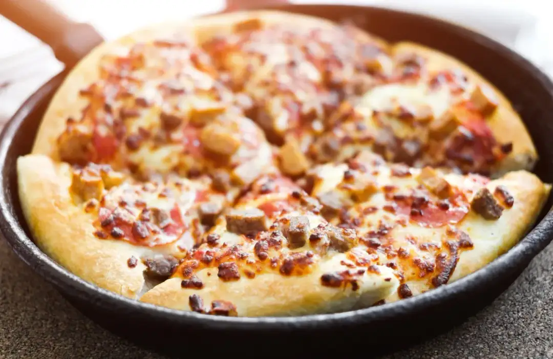 Pyszna pizza z patelni bez drożdży, z kawałkami mięsa i serem, gotowa do podania.