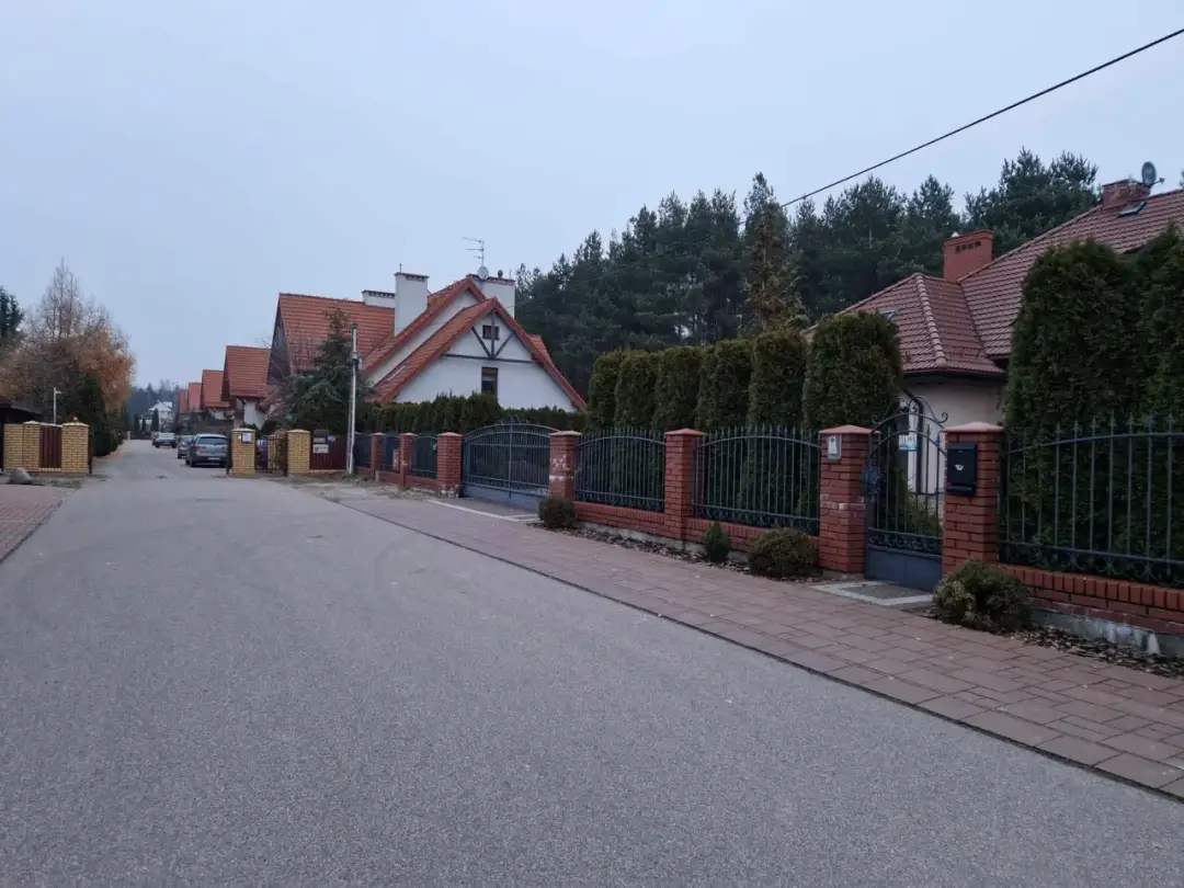Ulica w Białowieży z domami z czerwonymi dachami i żywopłotami. Może to dom Zenka Martyniuka w Białowieży?